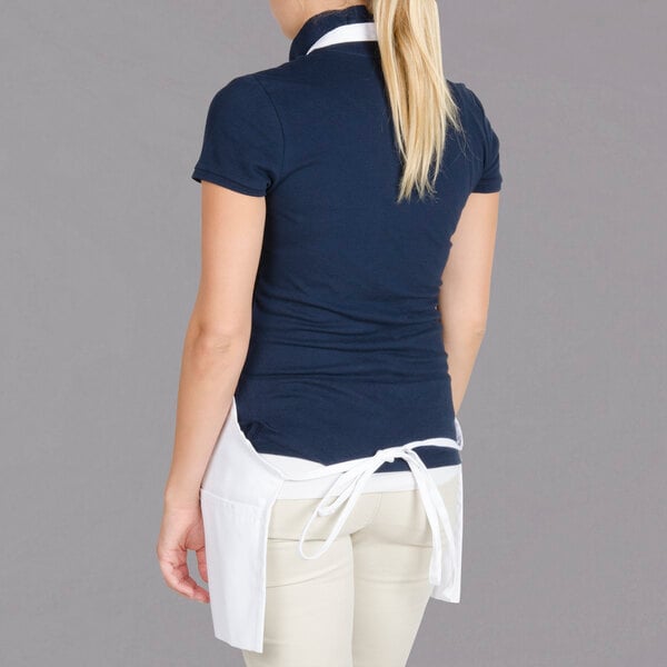 A woman wearing a white Chef Revival bib apron over a blue shirt and white pants.