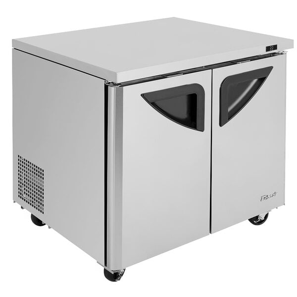 A Turbo Air stainless steel undercounter refrigerator with black handles on two doors.