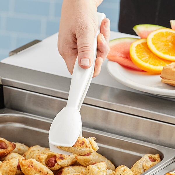 A person using Cambro white plastic tongs to serve food.