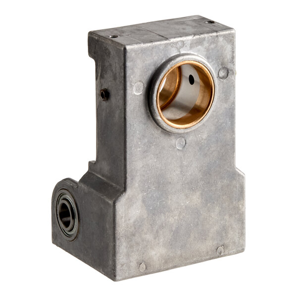 A rectangular metallic component with two circular openings, one larger and lined with a brass-like material, and the other smaller with a bearing visible inside.