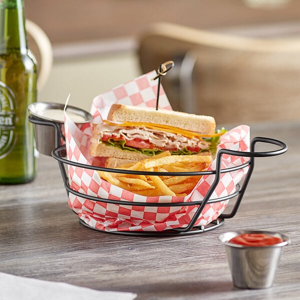 A sandwich and fries in an American Metalcraft black wire basket on a table.