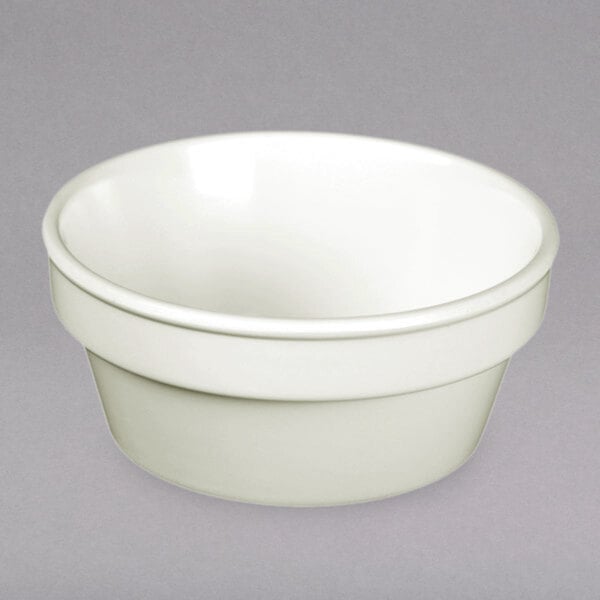 A close-up of a white Thunder Group Nustone melamine sauce cup.