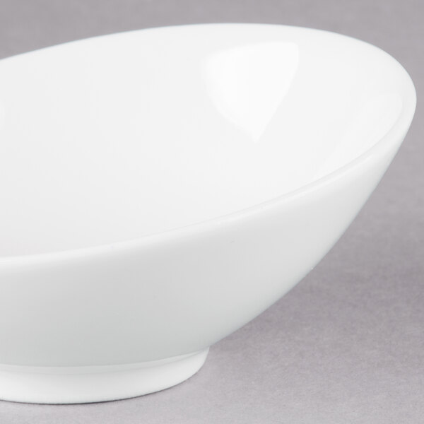 An Arcoroc white porcelain bowl with a small rim on a gray surface.