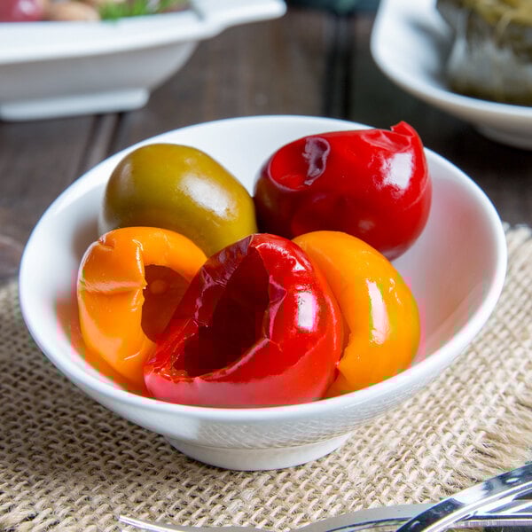 A bowl of red and yellow food in an Arcoroc Ludico bowl on a white table.