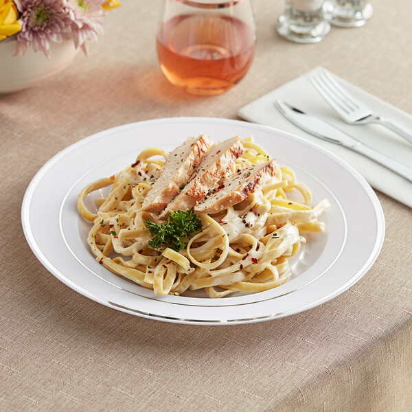 A Fineline white plastic plate with silver bands holding pasta with chicken and parsley.