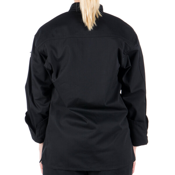 A woman wearing a black Mercer Culinary long sleeve chef jacket with cloth knot buttons.