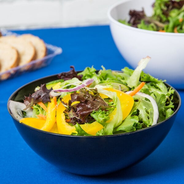 Garden-fresh salad in a black plastic serving bowl on top of a blue tablecover