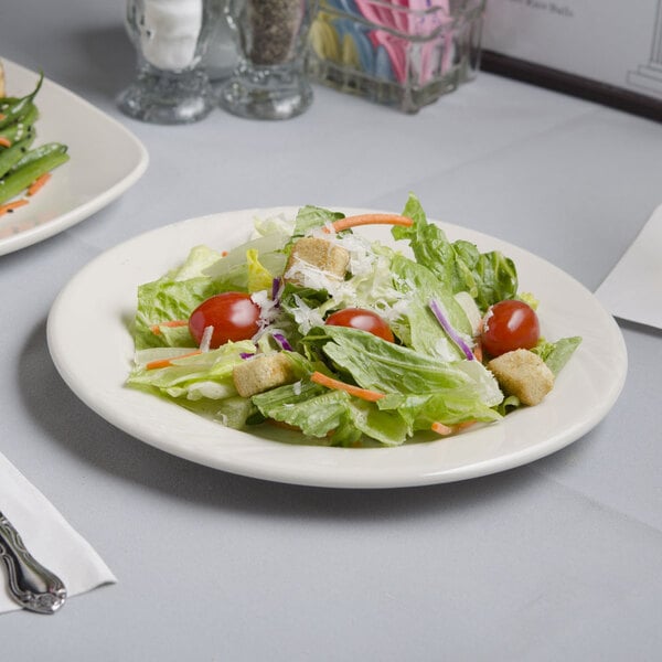 A Tuxton Monterey ivory china plate with a salad on it.
