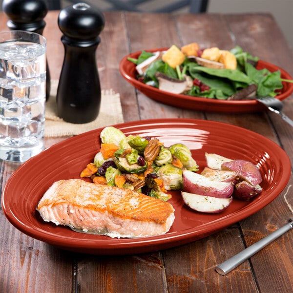 A Scarlet Fiesta china platter with food on a table with a fork and knife.