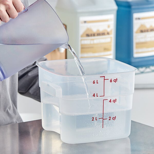 A person pouring clear liquid into a white container.