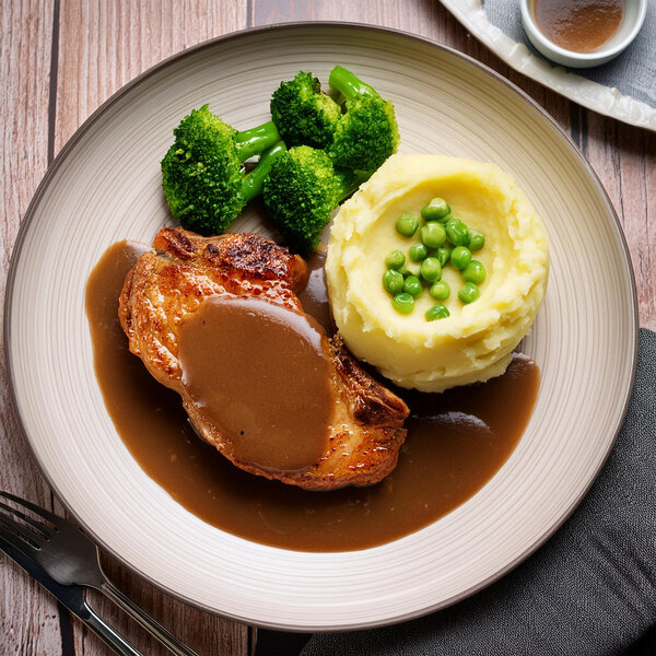 A plate of broccoli and mashed potatoes with brown pork gravy.