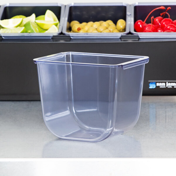 A clear plastic container holding limes on a counter.