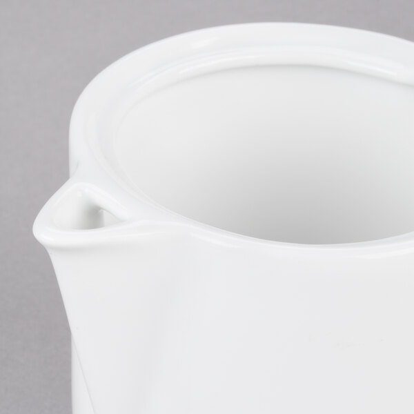 An Arcoroc white porcelain teapot with a lid and handle.