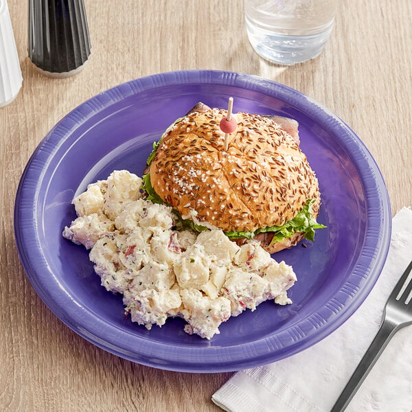 A purple Creative Converting plastic plate with food on a table.