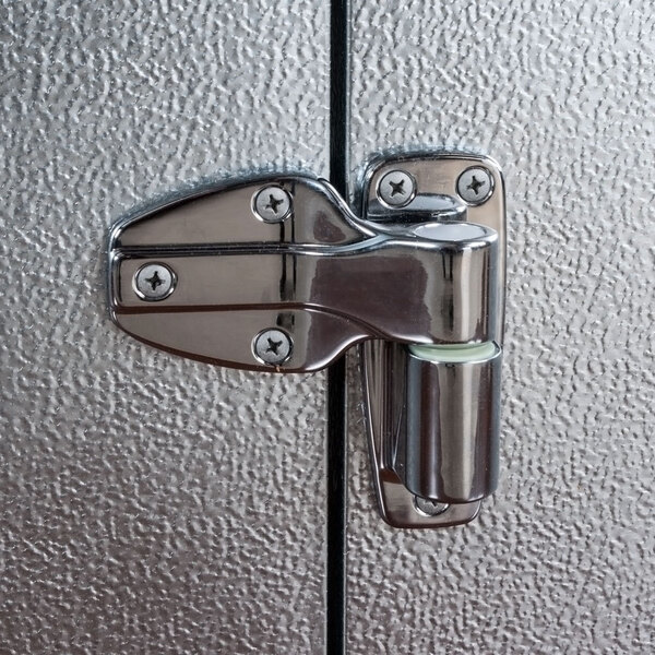A metal hinge attached to the door of an outdoor walk-in freezer.