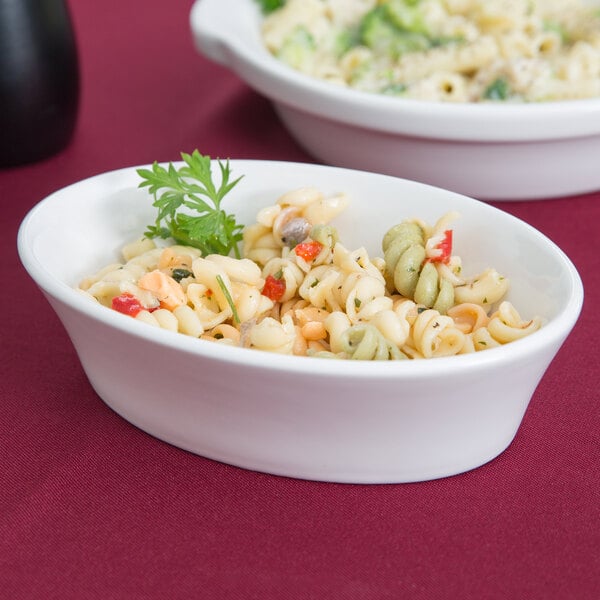 A Tuxton white china baker dish filled with pasta and broccoli.