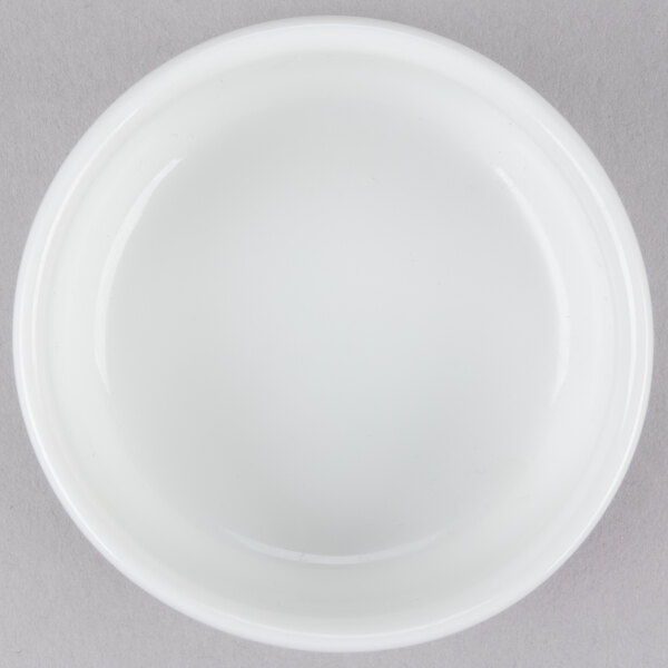 An Arcoroc white porcelain bowl on a gray surface.