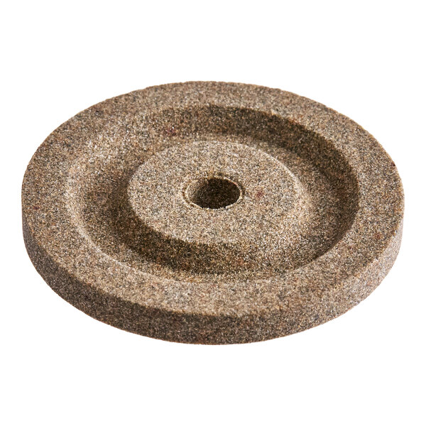A round, textured stone disc with a central hole and a recessed circular groove.