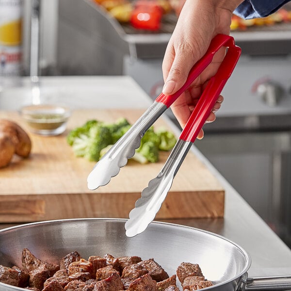 A person holding Vollrath Jacob's Pride tongs over food.