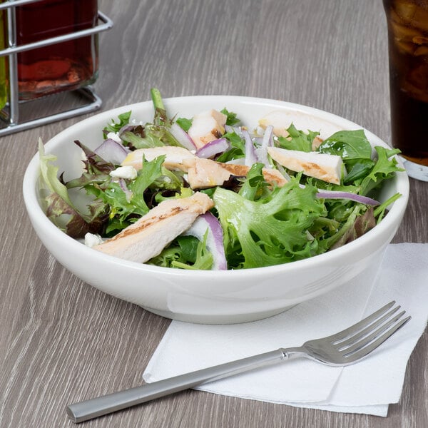 A Tuxton eggshell coupe bowl filled with salad with chicken and lettuce.
