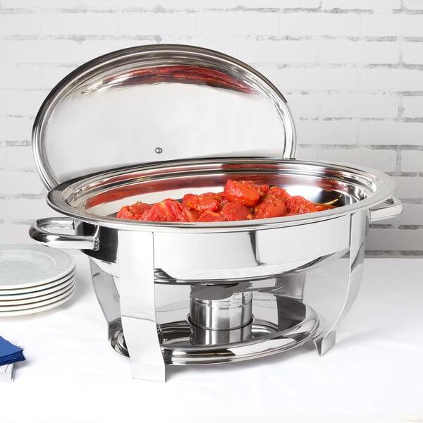 A Vollrath Orion stainless steel chafer with food inside on a table outdoors.