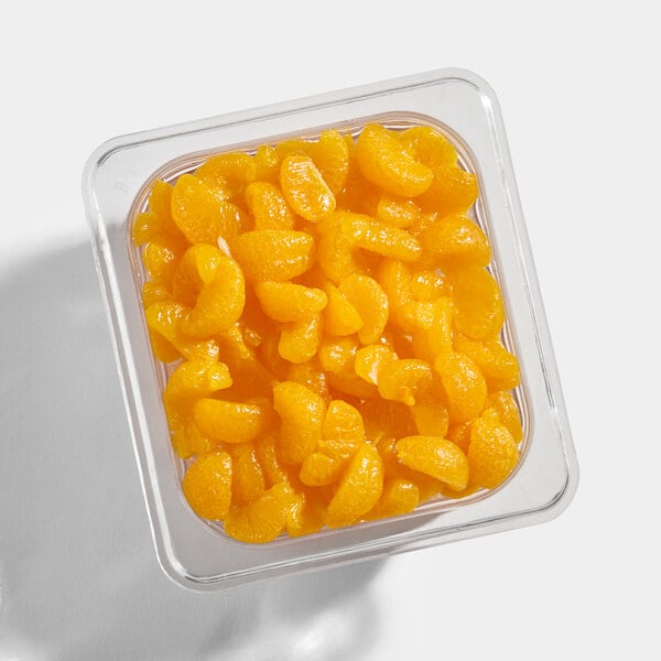 A clear plastic container filled with bright orange mandarin segments in syrup, viewed from above.
