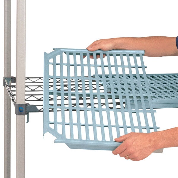 A person assembling a MetroMax Q plastic shelf grid.