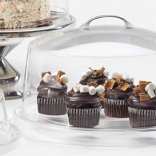 A clear plastic Cal-Mil cake cover on a table with cupcakes on a tray.