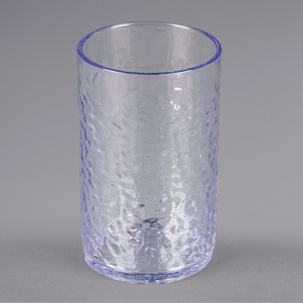 A close-up of a Carlisle clear plastic tumbler with a blue rim.