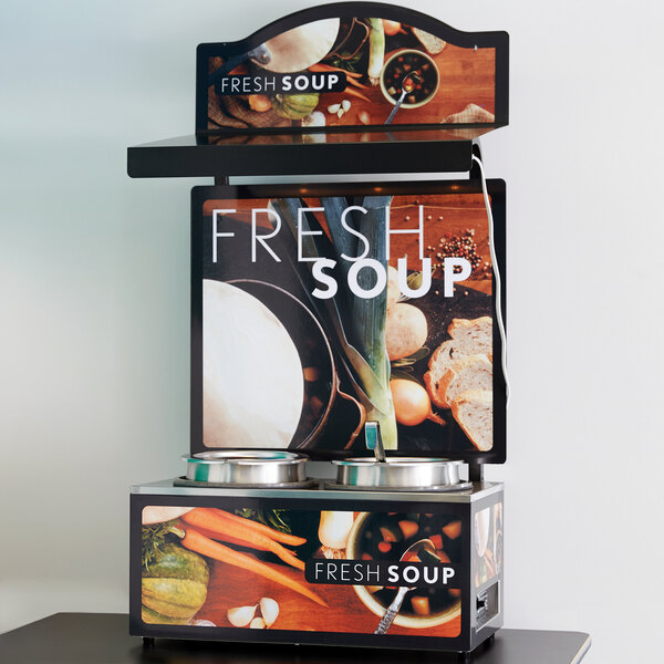 A Vollrath countertop soup merchandiser stand with Tuscan graphics and a menu board displaying fresh soup.