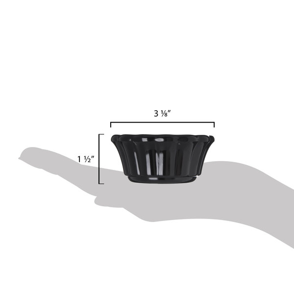 A hand holding a black Carlisle scalloped ramekin.
