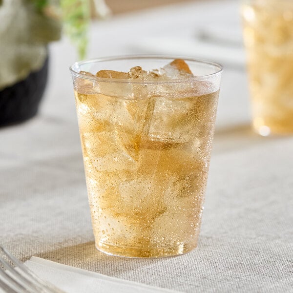 A clear hard plastic tumbler filled with a light-colored beverage and ice.