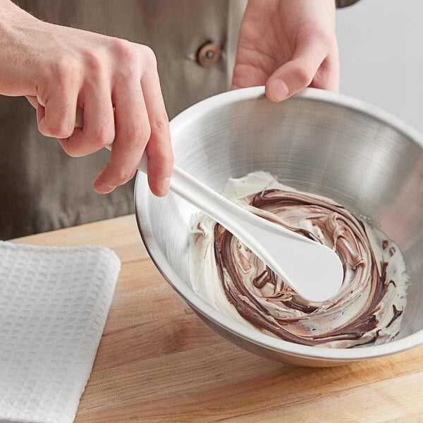 A person stirring food in a white bowl with a Mercer Culinary Hell's Tools Spootensil.