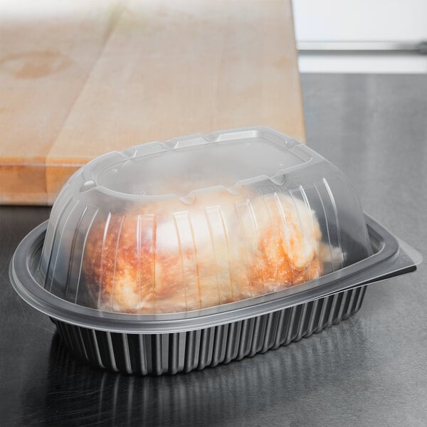 Whole roast chicken in a black plastic box with transparent lid