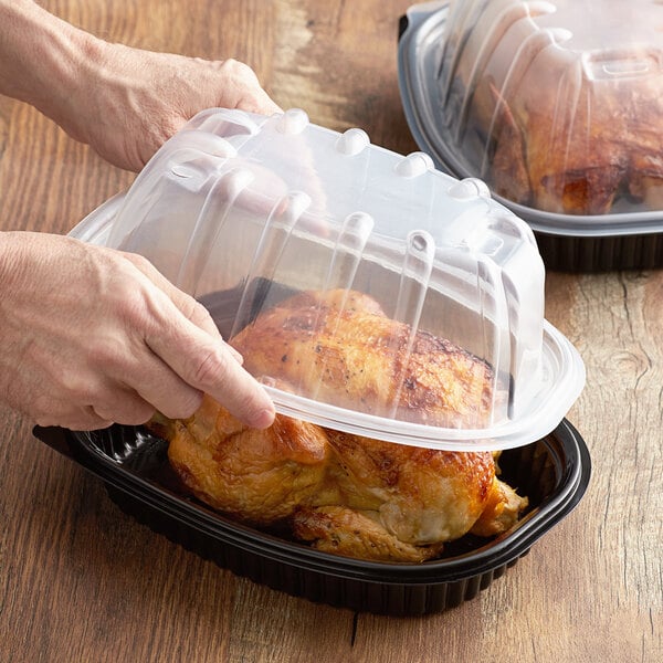 Two people holding plastic containers with chicken.