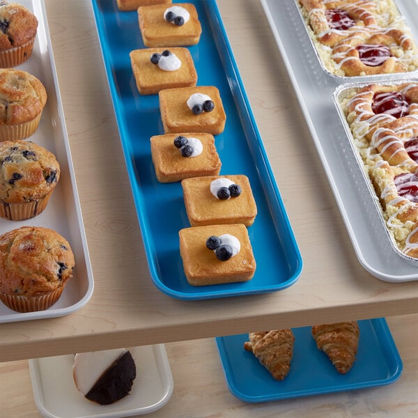 A blue Cambro market tray of pastries on a bakery display counter.