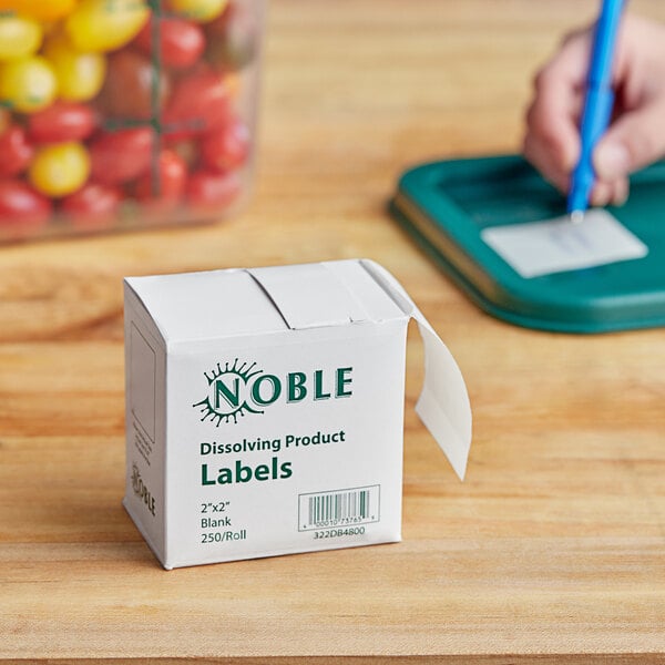 A small white box with green text and a yellow and red Noble label on a green scale.