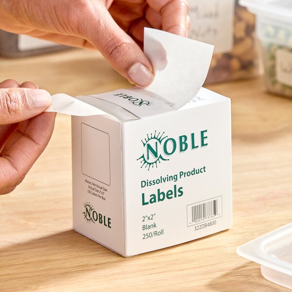 A box of Noble 2" x 2" blank dissolving product labels with a dispenser carton containing 250 labels per roll.
