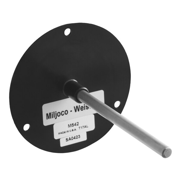A round black plate with four mounting holes and a metal rod protruding from its center, featuring a label with text.