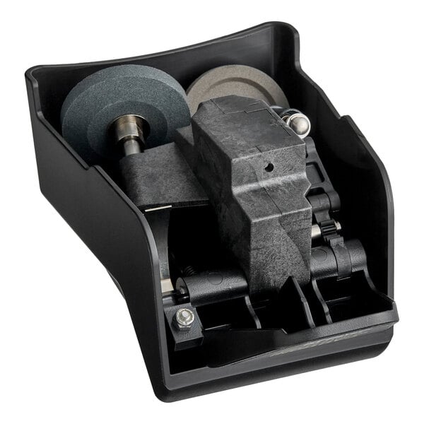 A black plastic housing containing two grinding wheels and mechanical components, likely part of a sharpening assembly.