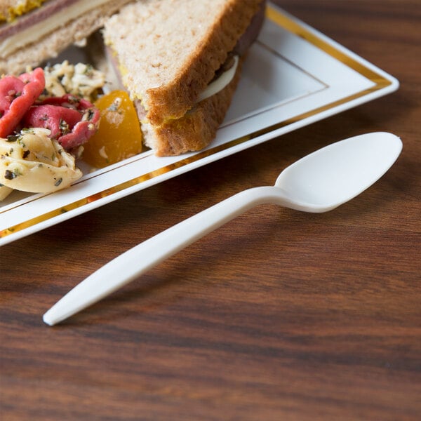 A plate of food with a sandwich and a cornstarch teaspoon on it.