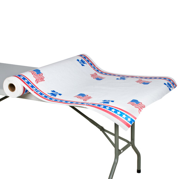 A roll of 40" x 300' patriotic paper table cover with red and blue designs on a table.