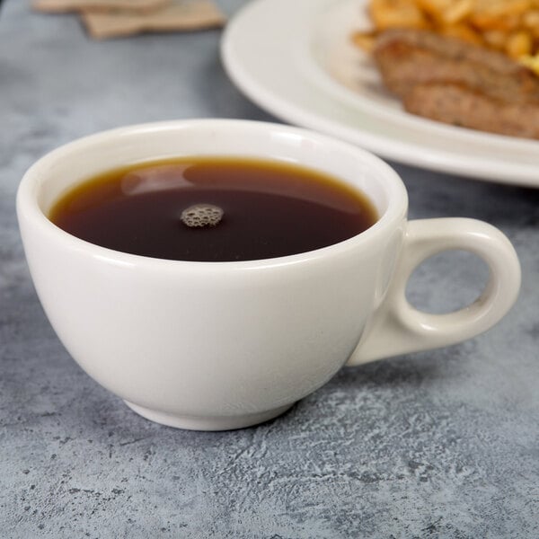 A Homer Laughlin ivory china cup filled with coffee on a saucer.