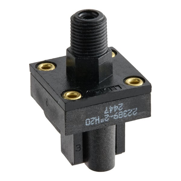 A black, square-shaped mechanical component with a threaded top connector, four brass-colored screw holes, and a cylindrical extension at the bottom.