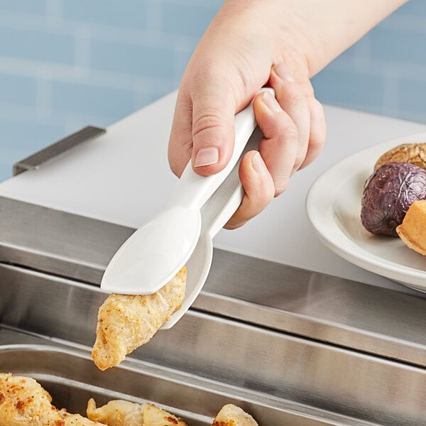 A person using Cambro white plastic tongs to serve food.