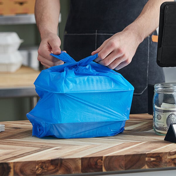 A person putting a blue T-shirt bag in a bag.