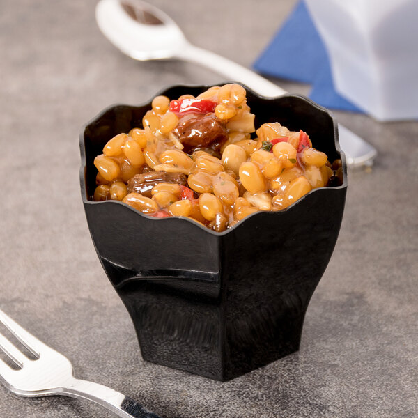 A black Fineline Tiny Temptations hexagon cube bowl with food in it.