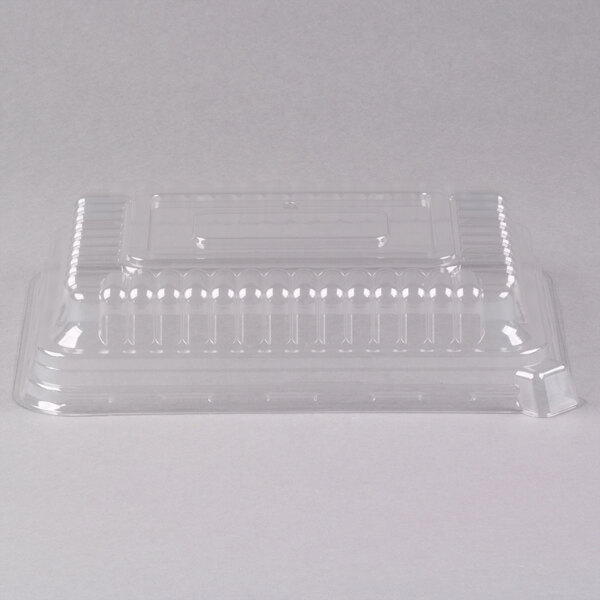 A clear plastic Fineline Flairware serving tray dome lid on a clear plastic tray.