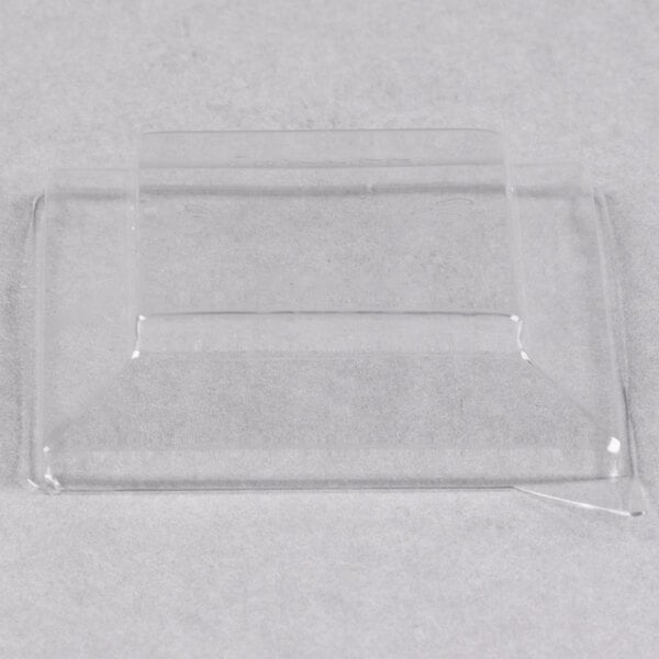 A clear plastic rectangular dome lid on a white surface.
