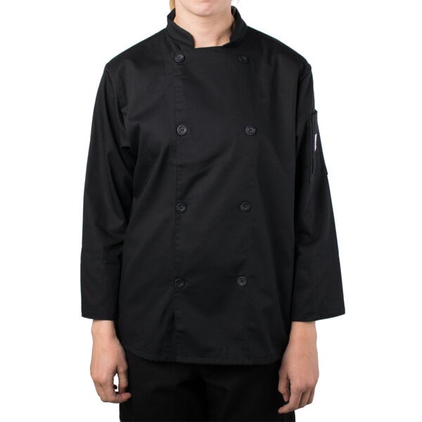 A woman wearing a black Mercer Culinary long sleeve chef jacket.